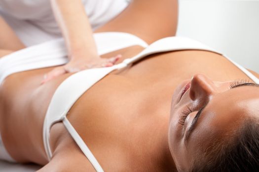 Woman at osteopathic massage with therapist hand on stomach.