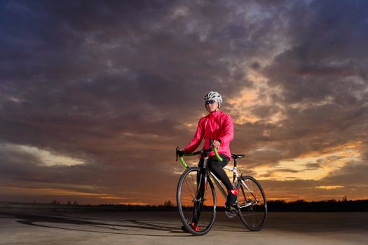 Portrait of Young Woman Cyclist with Road Bike at Sunset. Healthy Lifestyle and Outdoor Sport Concept