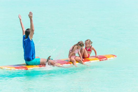 Family of dad and kid having fun stand up paddling together in the ocean