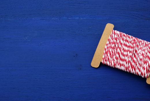 skein of craft red-white thread on a blue wooden background