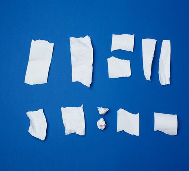 set of various pieces of torn white crumpled paper on a blue bac