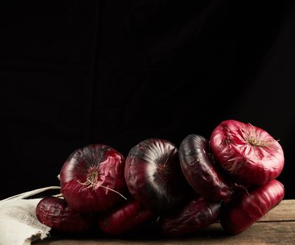 round red onion in husk on a gray linen napkin, black background