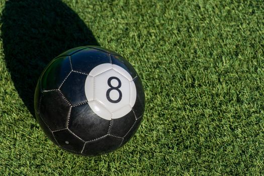 Black Eight (8) ball a soccer billiards or pool ball on green gr