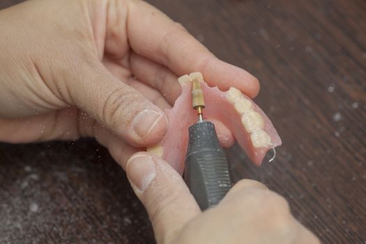 Dental technician make denture prothesis with motor tool in dent