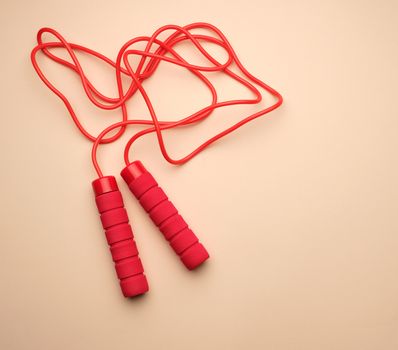 red sports rope for jumping and cardio load on a beige backgroun