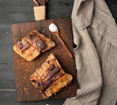 grilled pork ribs on a brown wooden cutting board,