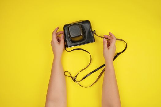 two female hands are holding an old film camera in a brown leath