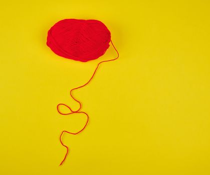 big skein of red wool on a yellow background