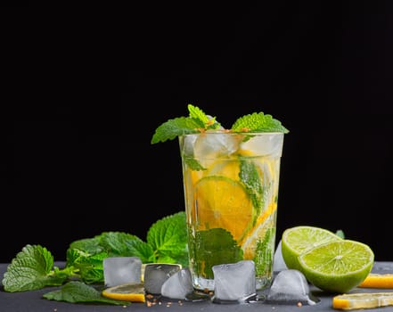  refreshing drink lemonade with lemons, mint leaves, ice cubes and lime in a glass on a black background, copy space
