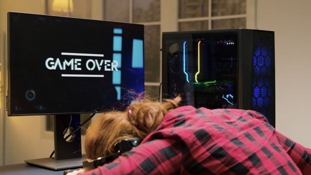 Woman with head on desk after losing a gaming competition