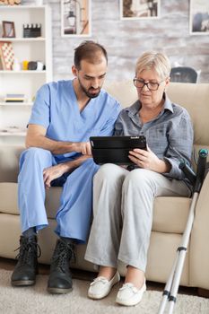 Young doctor reading diagnostic on tablet for senior woman