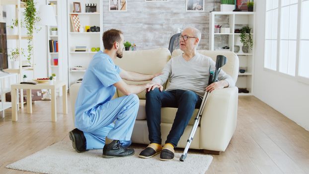 Revealing shot of male nurse checking on retired old man with alzheimer