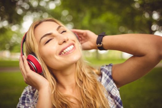 Smiling woman listening to music with eyes closed at park