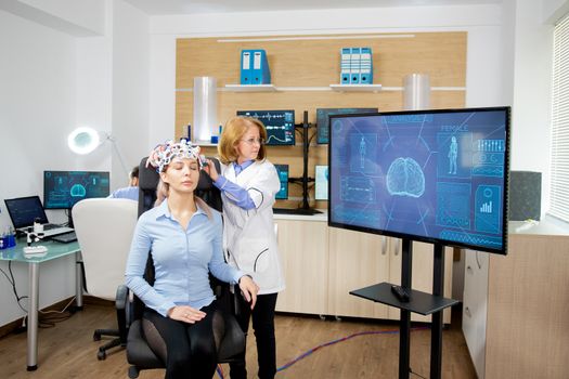 Doctor tracking the data transmitted by the brainwaves scanning headset on a large monitor