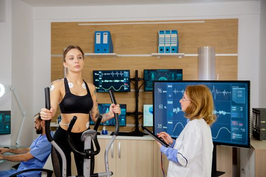 Female patient giving physical activity tests in the lab while a doctor supervises her