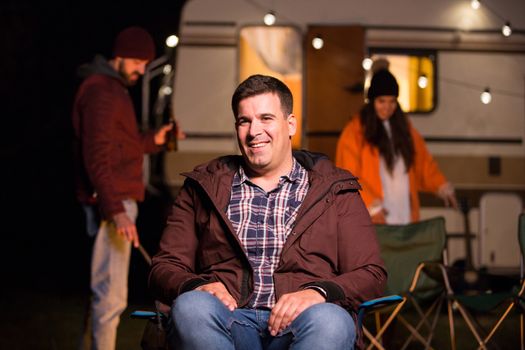 Portrait of young man smiling sitting on a camping chair