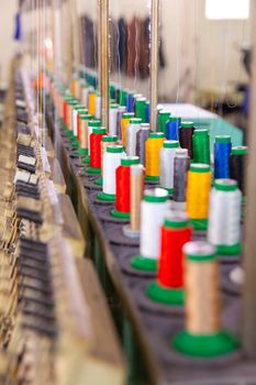 Close up with multicolored spools on an industrial embroidery machine