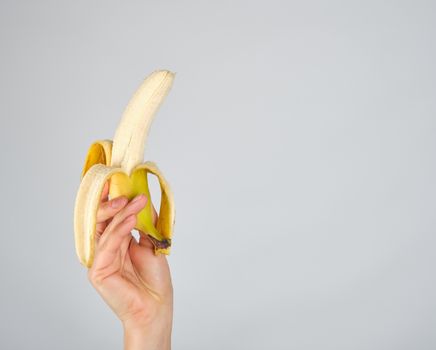 peeled fresh banana in female hand