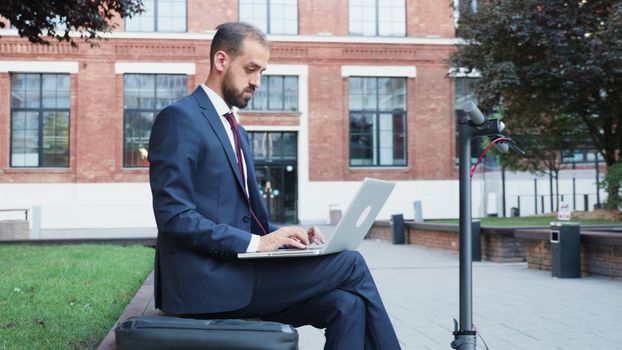 Man in suit sitting in business district working on the laptop