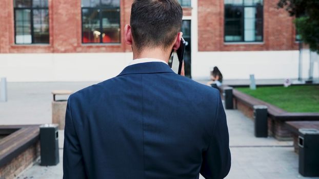 Back view of businessman having on conversation on the phone, slow motion