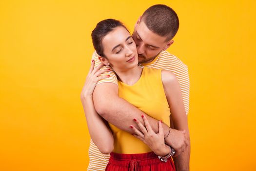 Girlfriend holding eyes closed while boyfriend hugs her from behind