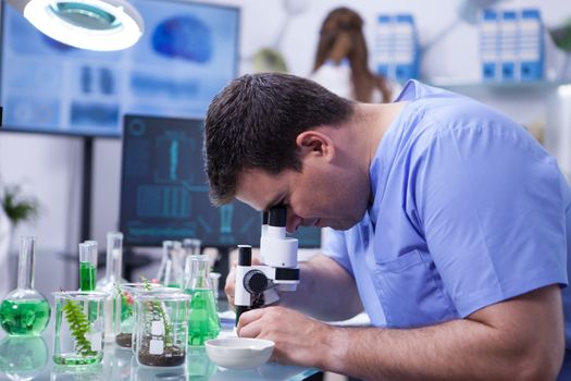 Caucasian scientist man in a biotechnology lab Looking through m