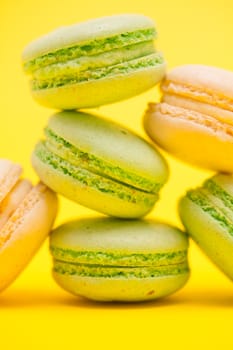 Close up of tasty variation of fresh macaroons on yellow background
