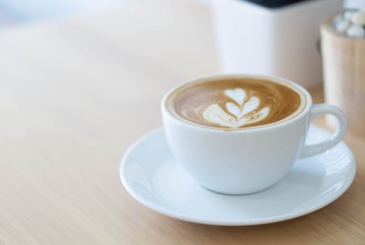 Closeup glass of latte art coffee tulip shape on wood background