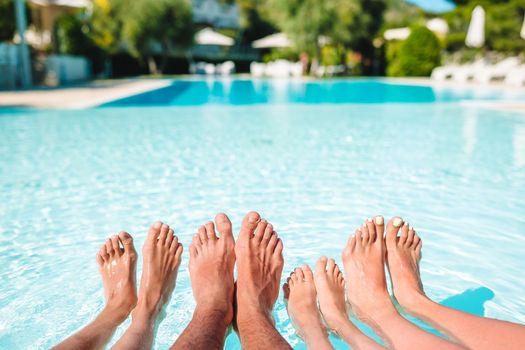 Close up of four people's legs by pool side