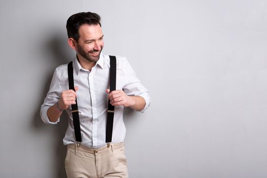 middle age man with suspenders smiling against gray background 