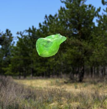 empty green garbage bag flies against the background of green pi