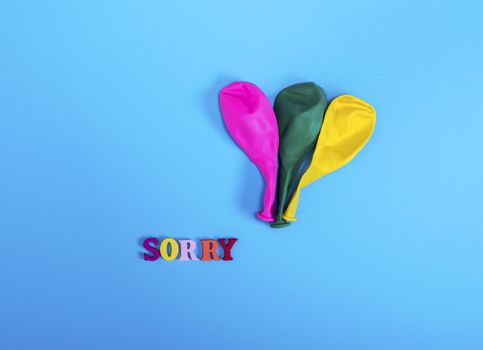 three blow off balloons and the word sorry 