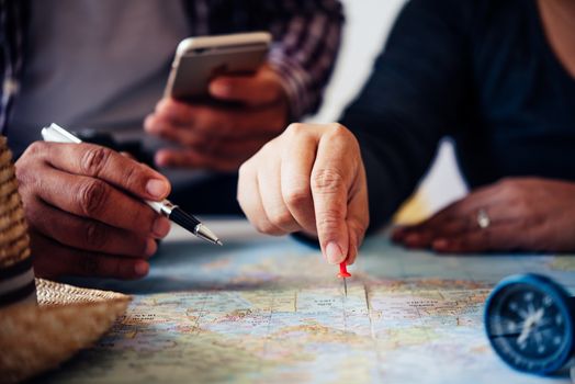 Travelers are planning a trip by searching the route on the map 