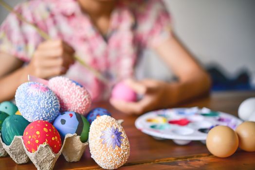 young girl painting Easter eggs for eastertime at home