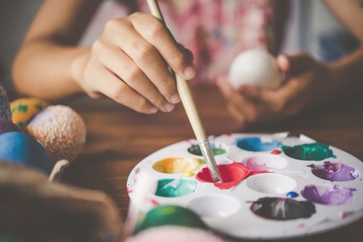 young girl painting Easter eggs for eastertime at home