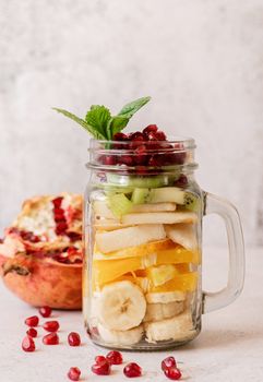 fruit salad in a mason jar on rustic concrete background front view