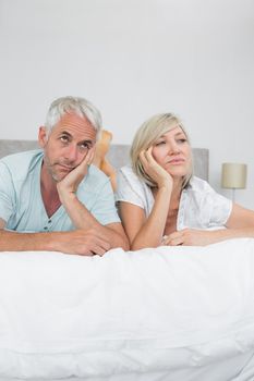 Displeased mature man and woman lying in bed