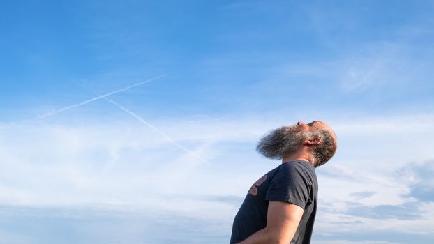 man looking up to the blue sky