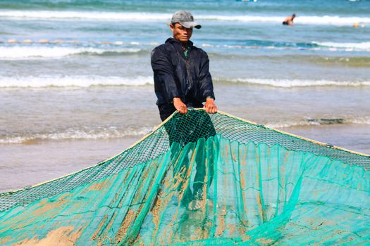 Editorial. Vietnamese Fisherman pulling a fishing net