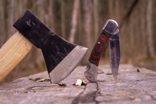 Hatchet or ax and pocket knife in a tree stump