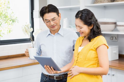 Happy expectant couple using tablet