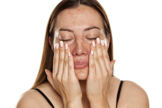 beautiful middle-aged woman applying moisturizer on her face