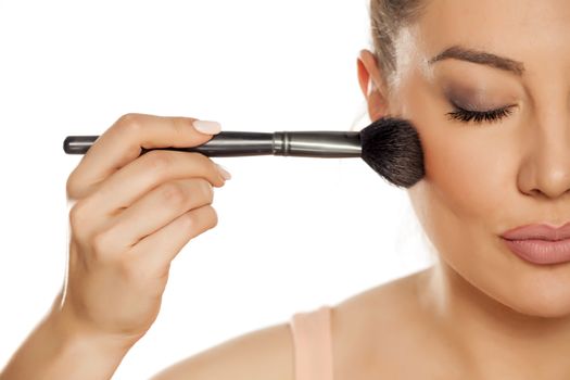 Young woman applying blush with brush