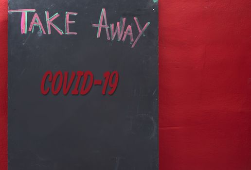 Take away text wrote on  grunge black board while Covid-19 over red background