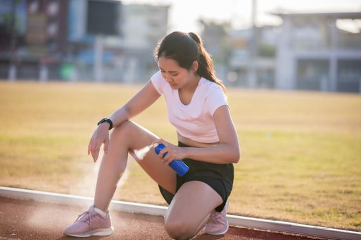 Asian Sports women using freezing spray for treating injured spo