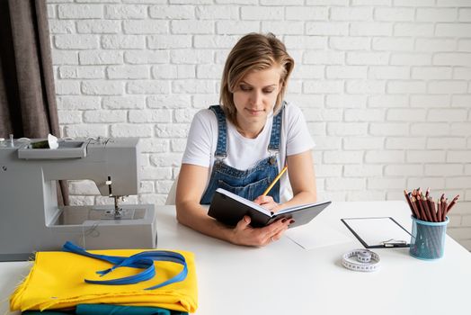 Young blond woman tailor drawing a sketch ready to sew