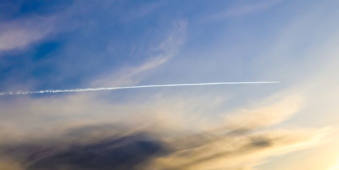 Aircraft condensation contrails in the blue sky inbetween some c