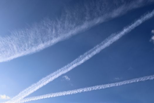 Aircraft condensation contrails in the blue sky inbetween some c