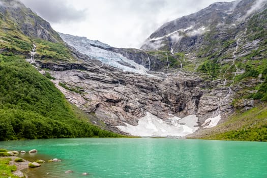 Boeyabreen Glacier in the mountains with lake in the foreground,