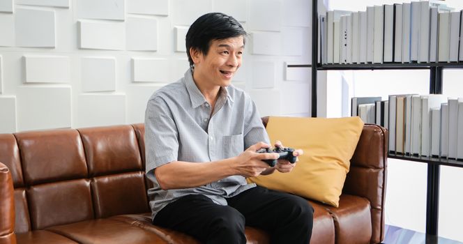 Senior Asian man using tablet and virtual reality simulator playing games in living room and feeling happy . Lifestyle Senior family at home concept.